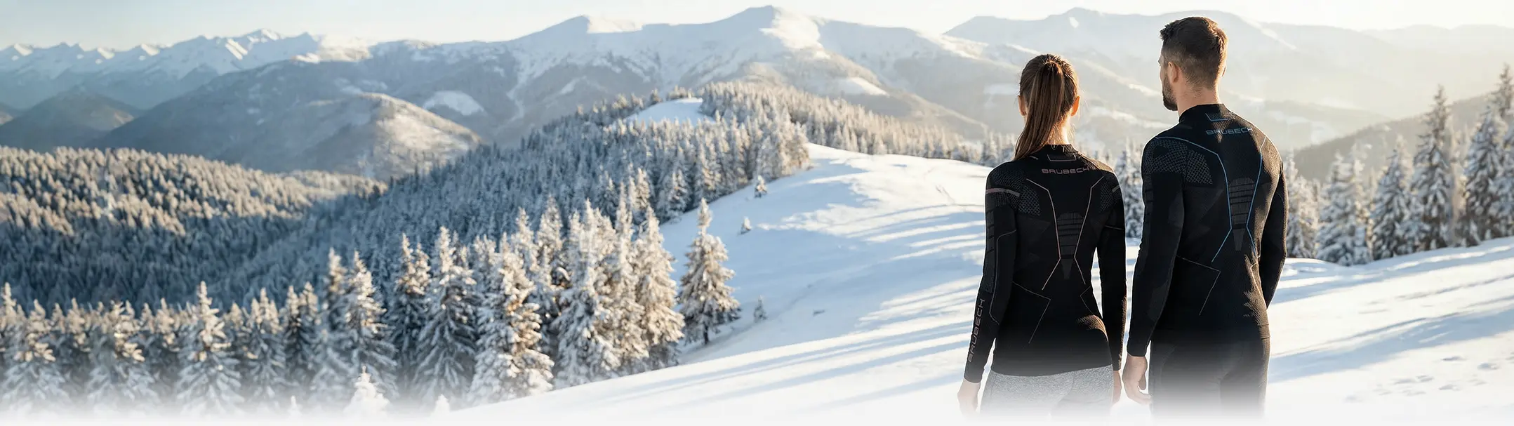 Férfi és nő fekete THERMO aláöltözet felsőben, háttal állva havas hegyes tájat néznek – Brubeck sport aláöltözet