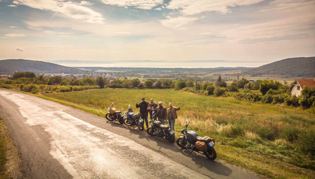 Négy motoros a motorjaik mellett egy balatonfelvidéki dombon, a háttérben a Balaton teljes panorámájával – ilyen kilátásért érdemes felkanyarodni a hegyoldalra